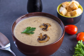 Mushroom cream soup in a brown plate on the table. Autumn vegetarian dish