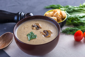 Mushroom cream soup in a brown plate on the table. Healthy autumn vegetarian traditional dish