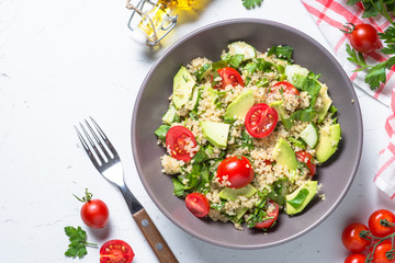 Quinoa salad with spinach, avocado and tomatoes top view.