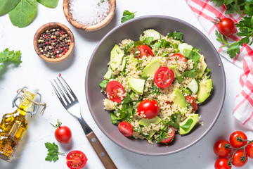 Quinoa salad with spinach, avocado and tomatoes top view.