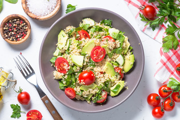 Quinoa salad with spinach, avocado and tomatoes top view.