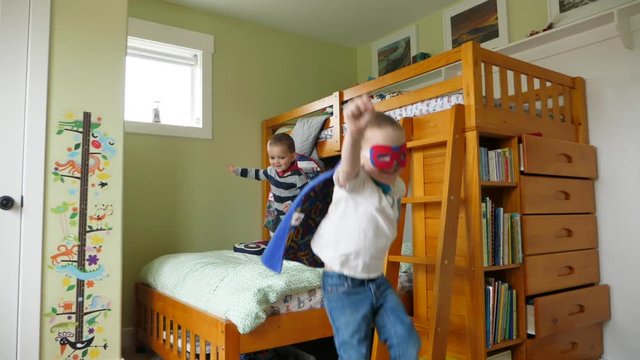 Slow motion shot of two cute brothers in their capes playing super heros