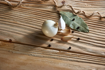 onion, garlic, black pepper and bay leaf on a wooden background