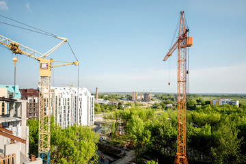 Landscape view on the construction site with building cranes during the sunset