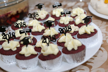 Chocolate cupcakes with white chocolate topping decorated graduation cap hat for happy graduation day party theme. Delicious sweet cake dessert.