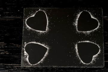 kształt serca usypany z cukru pudru na czarnej desce