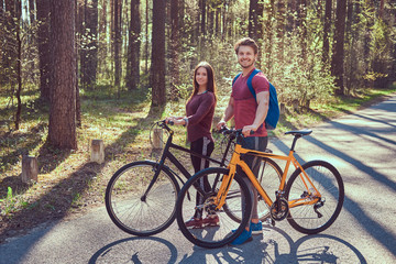 Fototapeta premium Group of young friends hiking through the forest with bikes on a beautiful summer day