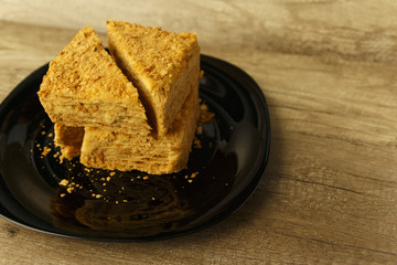 Slice of orange cake on black plate on the wooden table, food background