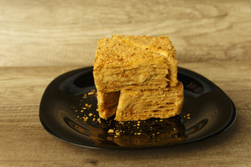 Slice of orange cake on black plate on the wooden table, food background