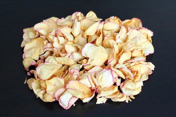 Dried rose petals on a black surface. Close-up. Isolated.