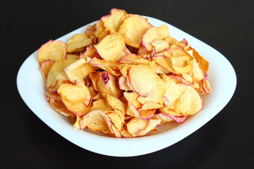 Dried rose petals on a white plate. Close-up. Isolated.