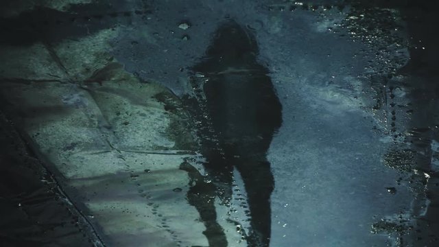 Man's shadow is reflected in puddle