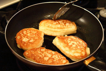 Preparation of pancakes in a frying pan on a gas stove. Fritters. Pancakes with milk. Close-up.