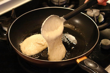 Preparation of pancakes in a frying pan on a gas stove. Fritters. Pancakes with milk. Close-up.