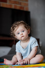 little curly baby boy sitting at floor in loft flat.