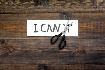 I can concept. Motivate youself, believe in yourself. Sciccors cut the letter t of written word I can't. Dark wooden background top view copy space