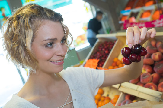 young woman buying cherries a weekly market