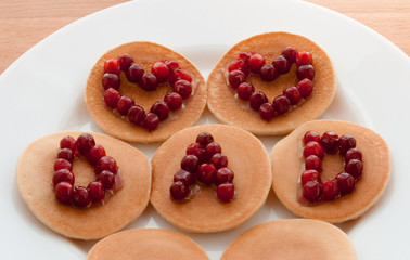 Pancakes with maple syrup and cranberries on a white plate. Concept Father’s day. Greeting Card, Gift, Surprise. Two Hearts and text Dad. Idea Family Brunch, Breakfast. Snacks. Sweets. Food.