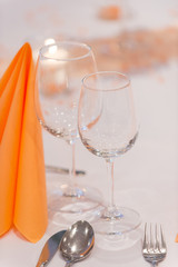 Wineglasses and folded table napkin tishue on restaurants table covered with white tablecloth. Cutlery and wineglasses served in restaurant, close up. Restaurant service concept