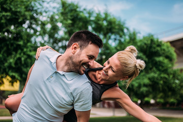 Close-up portrait of smiling young couple piggybacking outdoors.