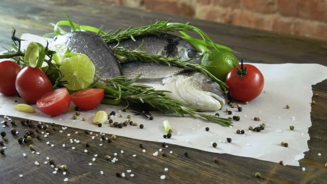 Ingredients for cooking fish. Fresh sea bass, green onions, lime, garlic cloves, rosemary, seasoning. 4K