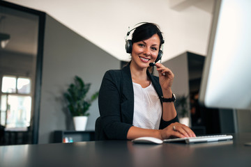 Portrait of happy female customer support operator at workplace.