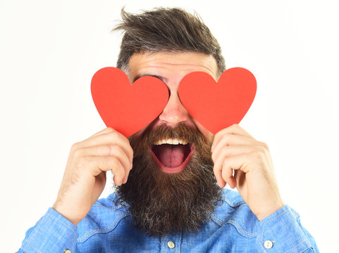 Blinded by love concept. Man with beard holds red hearts