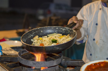 Cooking fresh yellow pasta in frying pan on flames