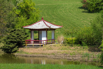 gazebo with white roof stands on the shore of the lake