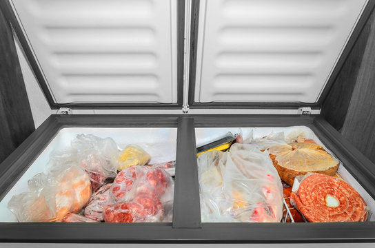 Frozen food in the freezer. Bagged frozen meat and other foods in a horizontal freezer with the two doors open. Food preservation.