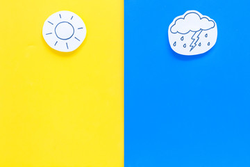 Good and bad weather concept. Template for forecast. Sun vs cloud and lightening with rain on yellow and blue background top view copy space