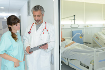 doctor and nurse consulting outside hospital room