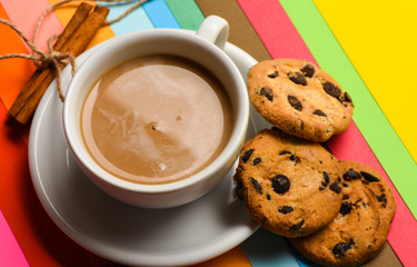 Coffee break concept. Drink with caffeine or cocoa with milk. Coffee on colorful positive background. Cup of coffee with milk or cappuccino with cookies and cinnamon on colorful background