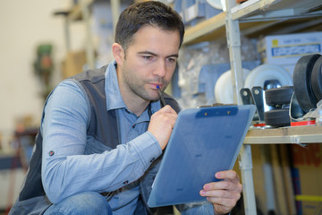 serious delivery man with clipboard in warehouse