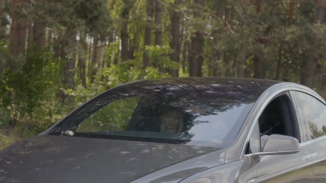 Young couple riding in luxury car in the forest in slow motion