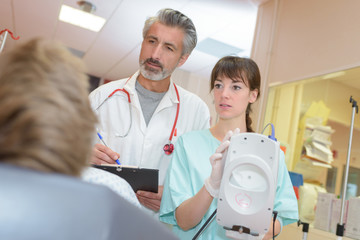 doctor and nurse with patient measuring blood pressure