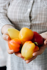 Woman holding hip of fresh bell peppers in hands.