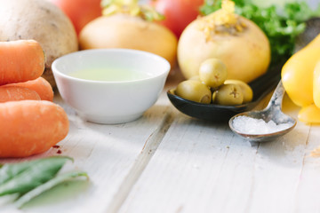 Vegetables, olives and spices over white wooden table.