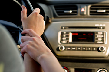 A couple of girls in the front seats of the car on the way to the sunset. She's driving, she's holding her hand. Shooting close-up about driving safety. Chase the sunset! Travelling sweethearts