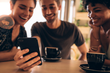 Friends at cafe using mobile phone