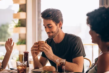 Zelfklevend Fotobehang Man eating burger with friends at restaurant © Jacob Lund