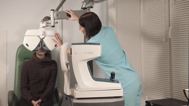 the doctor the ophthalmologist adjusts or adjusts the device orropotor for measurement of a refractive error of an eye, the patient is in a polyclinic