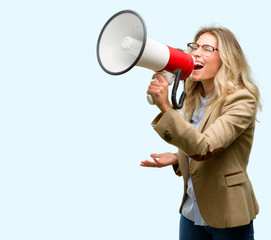 Young beautiful woman communicates shouting loud holding a megaphone, expressing success and positive concept, idea for marketing or sales