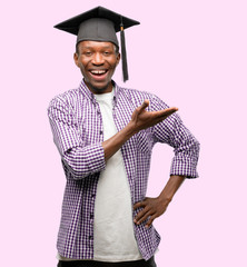 Young african graduate student black man holding something in empty hand