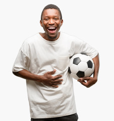 African black man holding soccer ball confident and happy with a big natural smile laughing