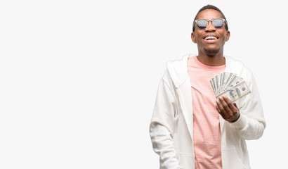 African man holding dollar bank notes thinking and looking up expressing doubt and wonder