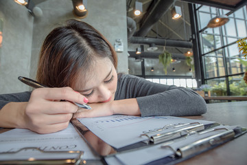 Young attractive Asian business woman sleeping, drowsing or taking a nap at her desk, Tired...