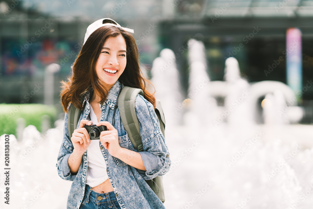 Wall mural young beautiful asian backpack traveler woman using digital compact camera and smile, looking at cop