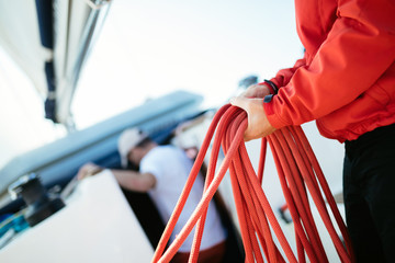 Young handsome sailor pulling rope on sailboat