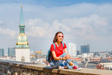 Fototapeta na wymiar Traveler woman tourist with backpack and sunglasses resting at observation point to Bratislava city